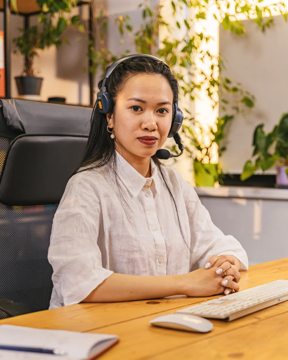 A medical receptionist taking a call on a headset at her desk